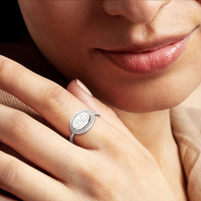Diamond halo sterling silver monogram ring worn on finger, oval engraved center