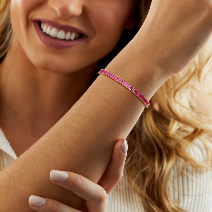 Pink ruby tennis bracelet on wrist with gold clasp detail