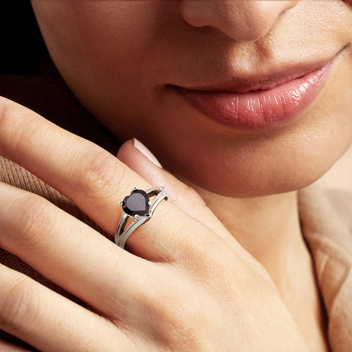 Sterling silver heart garnet ring on finger, close-up of dark red gemstone