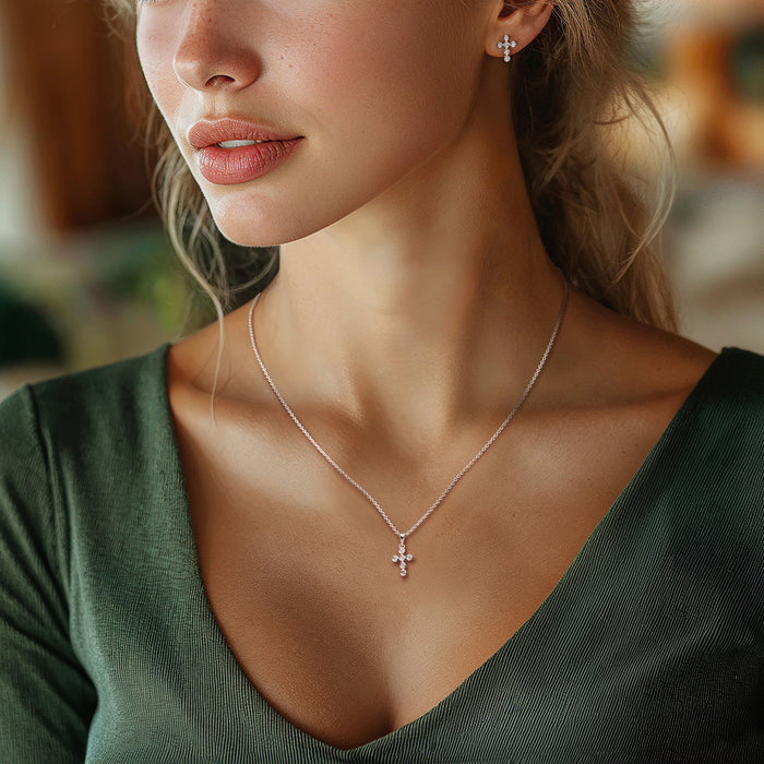 Sterling silver cross pendant necklace with matching cross stud earrings on a wearer