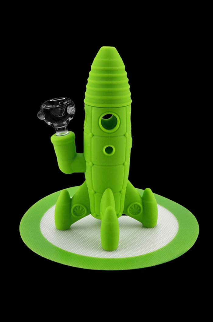 Green silicone rocket ship-shaped water pipe with a glass bowl, displayed on a textured mat.