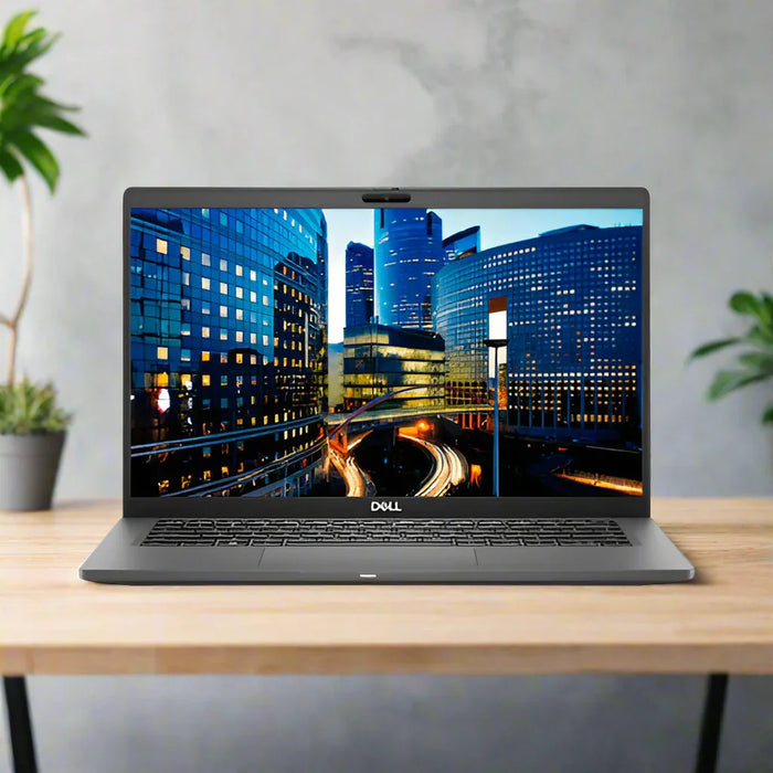 A refurbished Dell Latitude 7410 i5 10310U 16GB 256GB SSD business laptop sits on a wooden desk, its 14 screen powered by Windows 11 Pro and displaying a cityscape with sunset light trails. Brand: Dell. Includes 1-year warranty.
