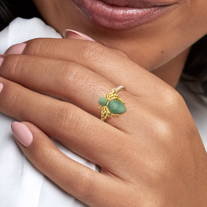 Gold-tone bee ring with green jade stone on wearer’s finger, close-up