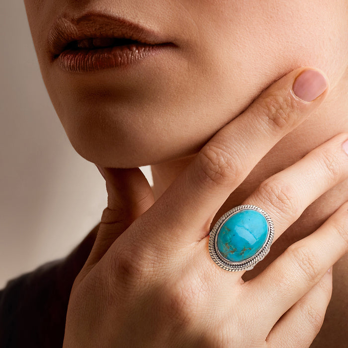 Turquoise oval stone sterling silver ring on hand with braided metal border